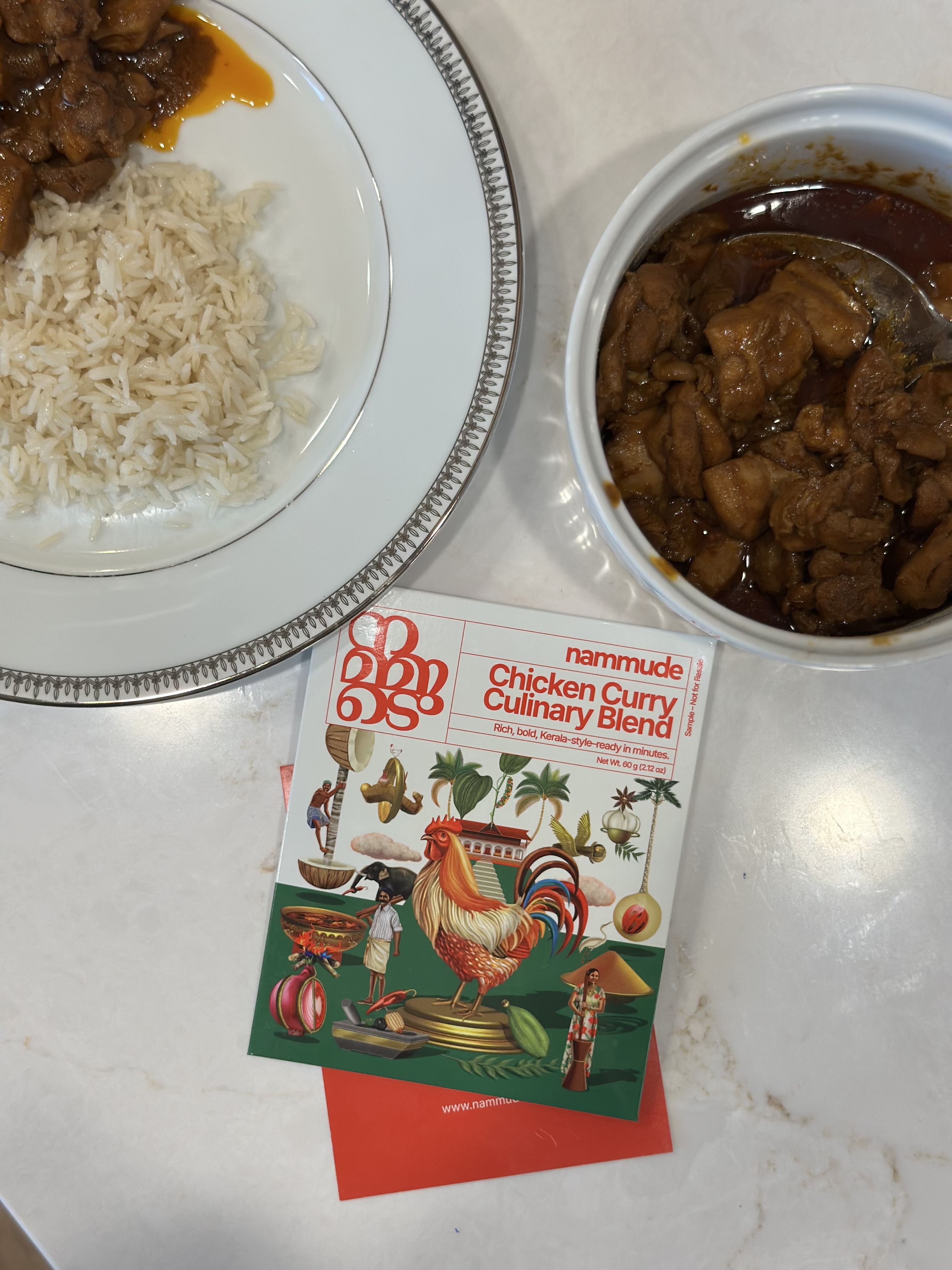 Kerala-style chicken curry served with basmati rice, beside a Nammude Chicken Curry Culinary Blend packet